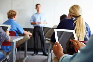 Close Up Of Pupil Using Digital Tablet In Classroom